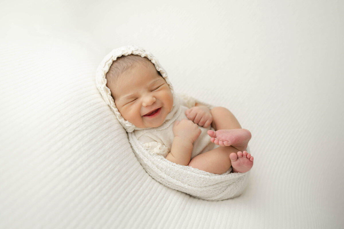 precious oklahoma newborn laughing wearing a bonnet