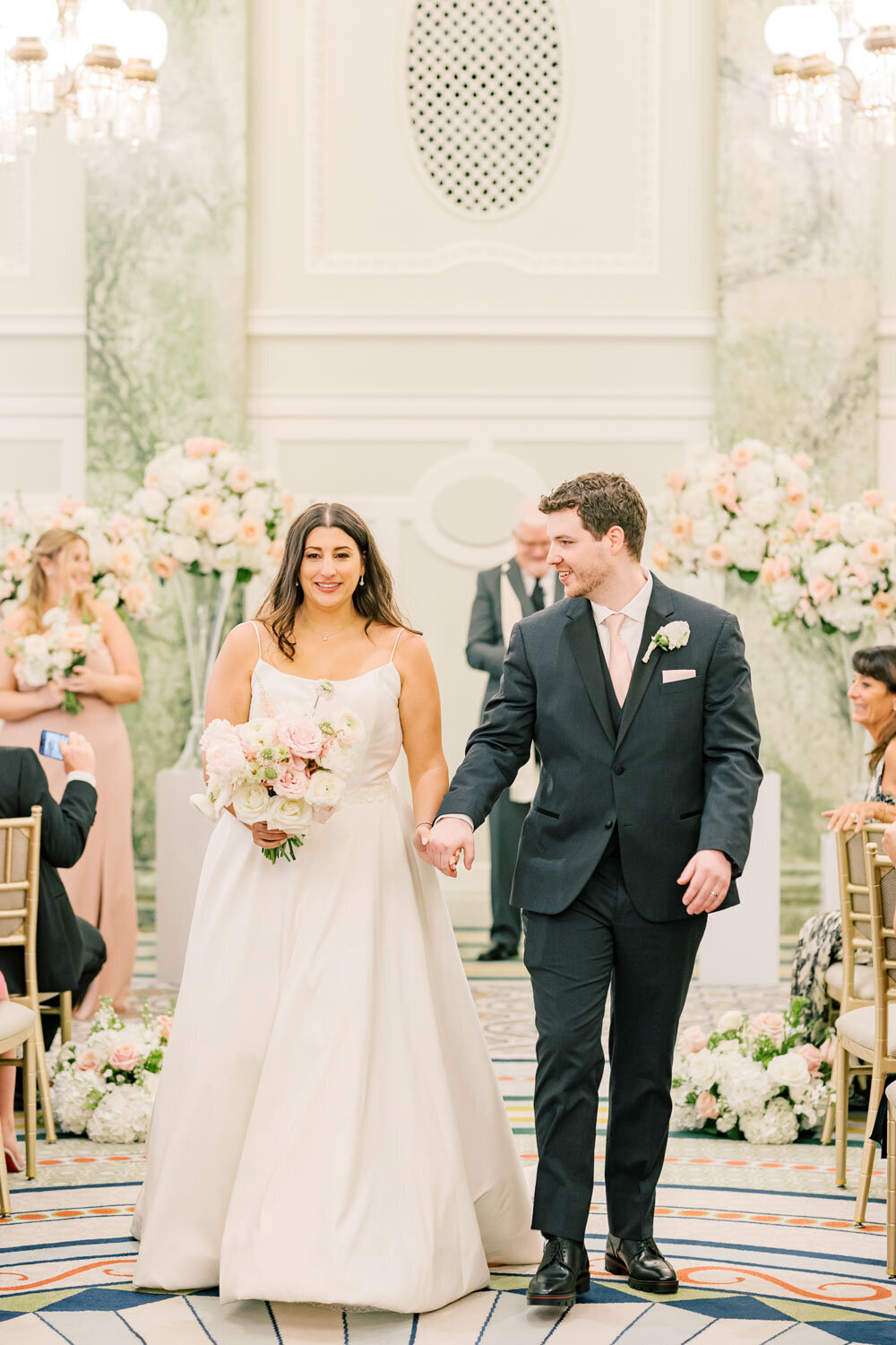 Bride and groom walking down the aisle smiling.