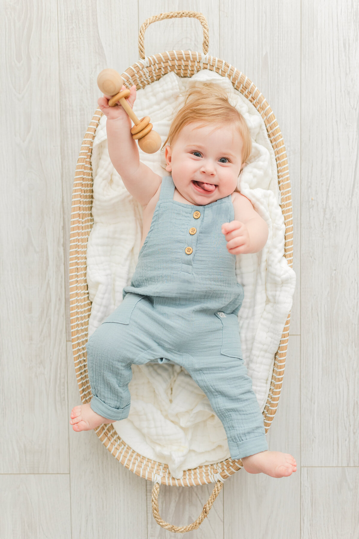 A Baby Photography photo in Northern Virginia of a baby holding a rattle in a basket on the floor