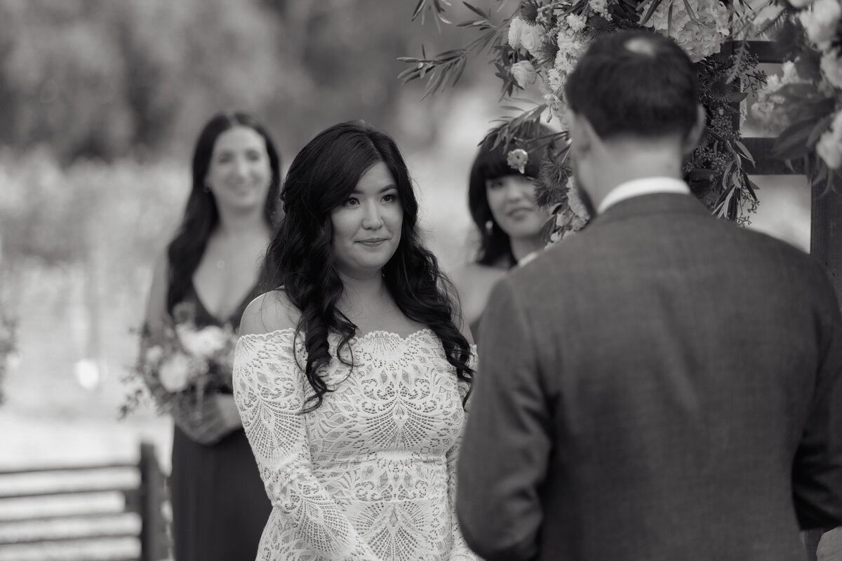 A touching moment as the bride shares her vows under a floral arch at a Napa Valley wedding, beautifully documented by a Northern California photography team.