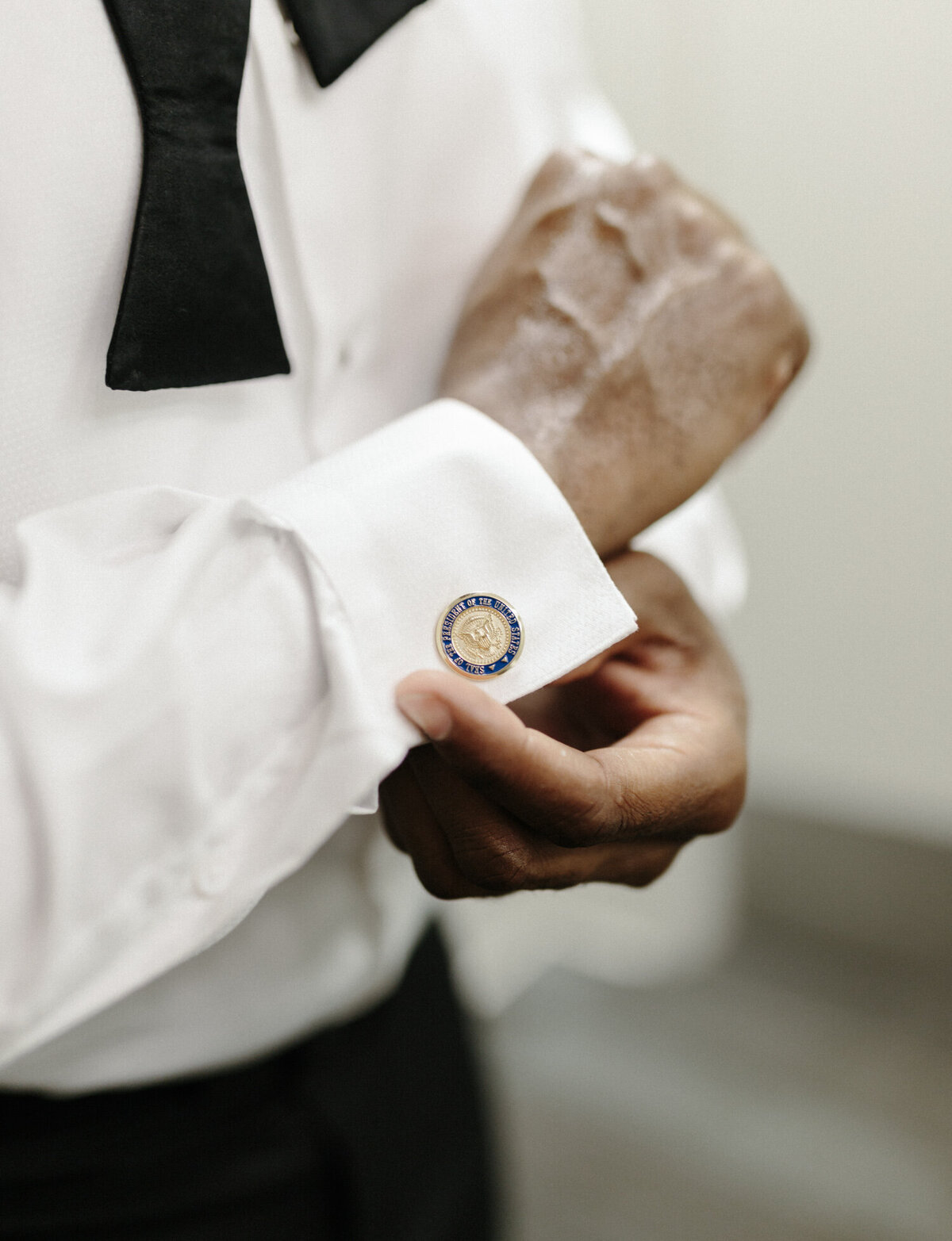 a groom fastens his cufflinks with presidential seal, Detroit, Michigan