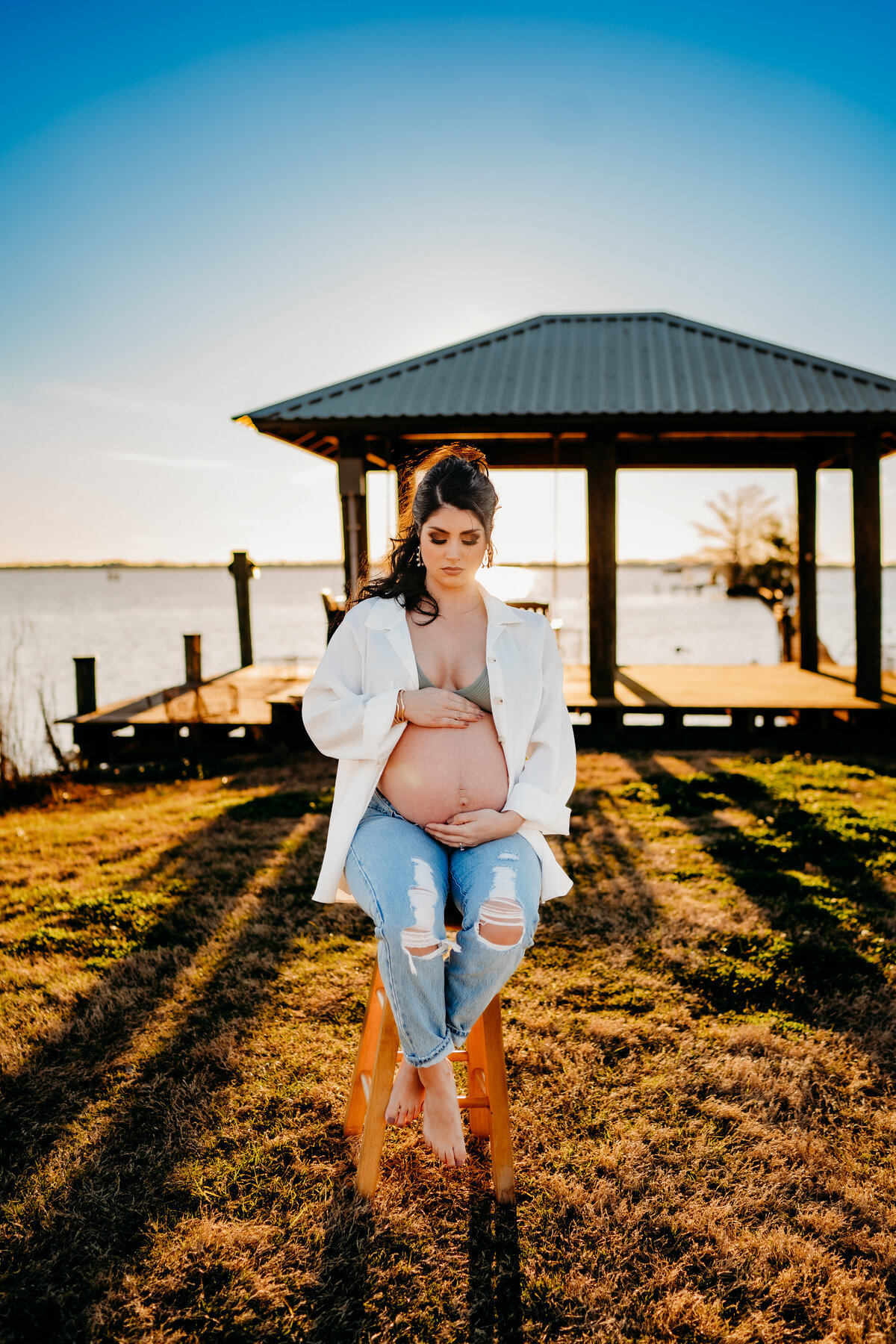 Casual pregnancy pose, holding belly, on stool at lake peigneur, new Iberia, la
