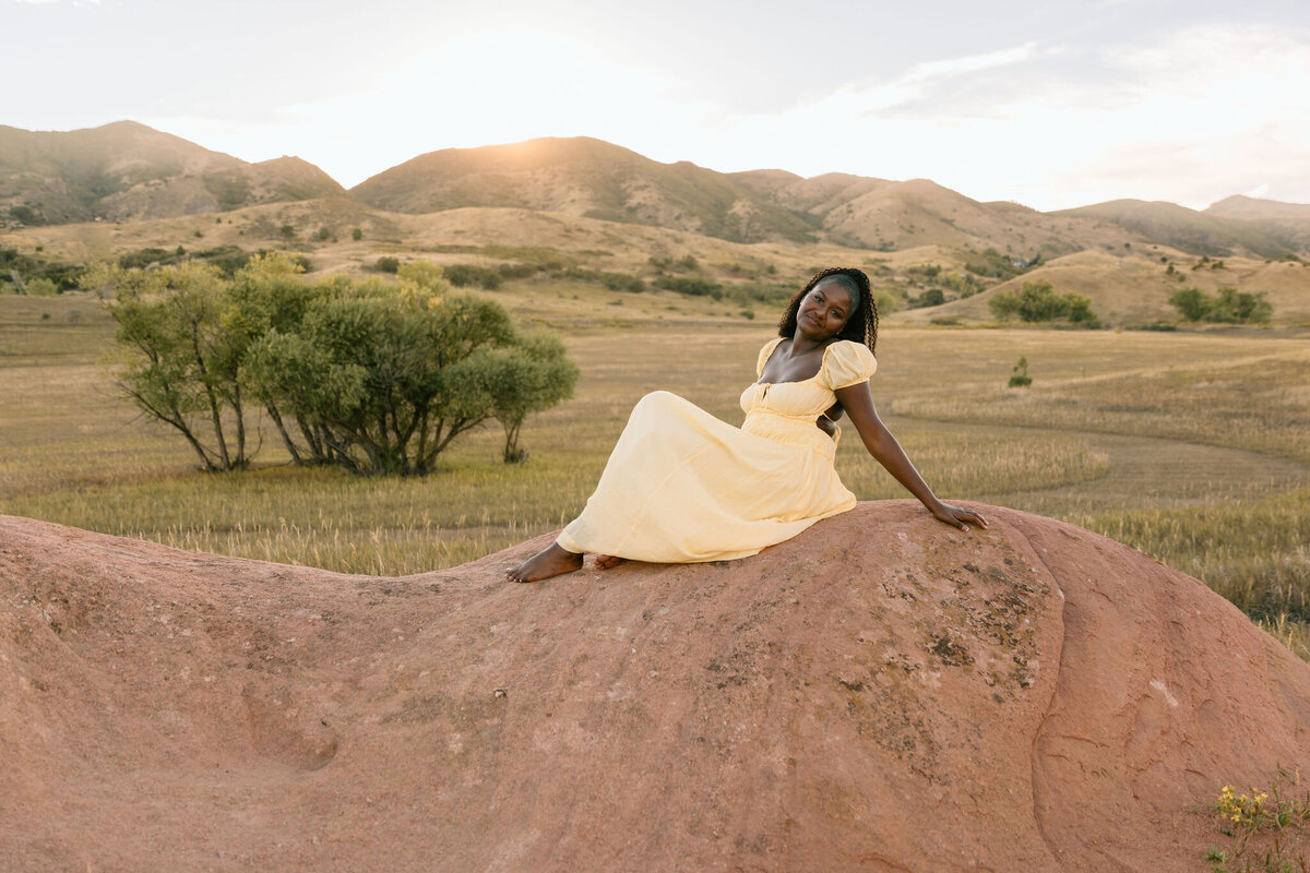 Woman tourist  photoshoot laying on red rocks with mountains