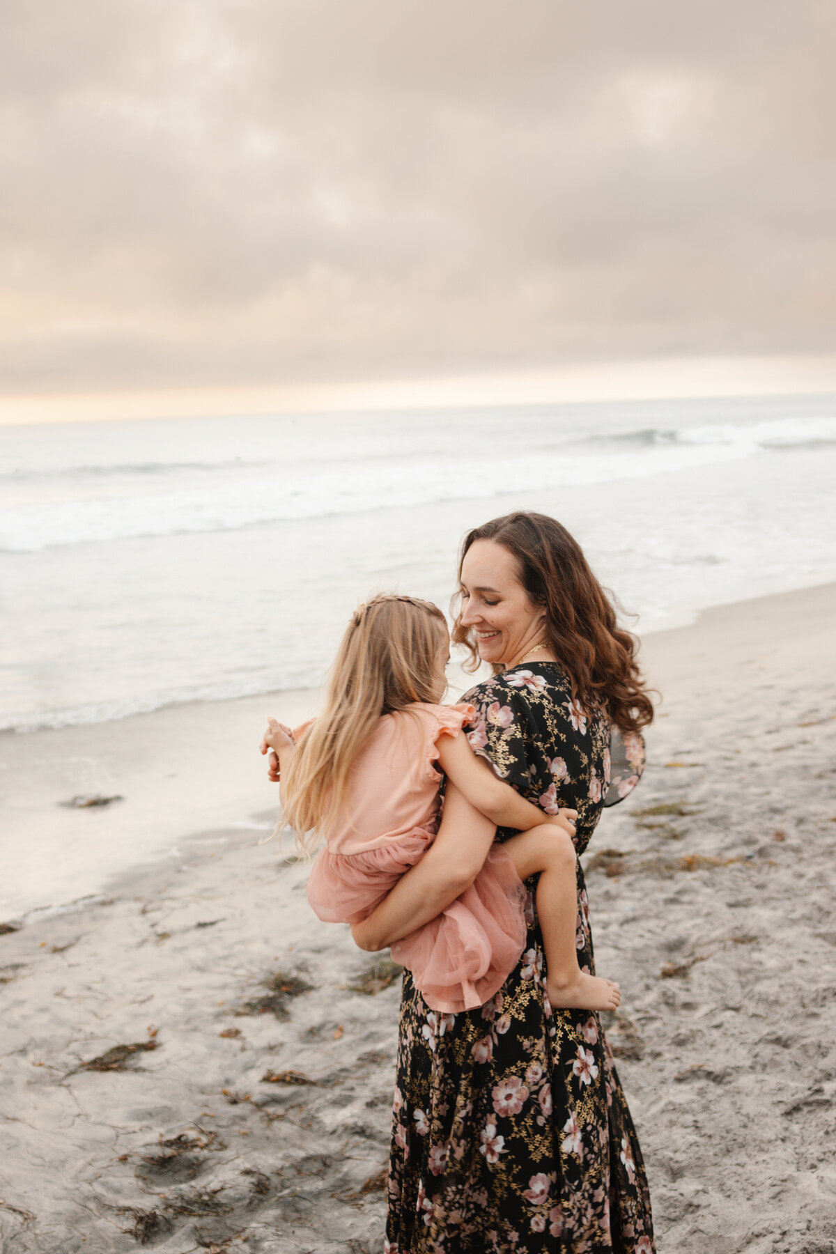 mom and daughter dance on the beach