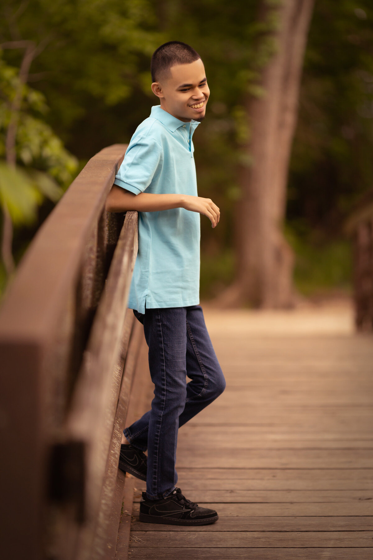 A young man poses on a wooden bridge for his Dallas family photography session, captured by a Dallas family photographer.