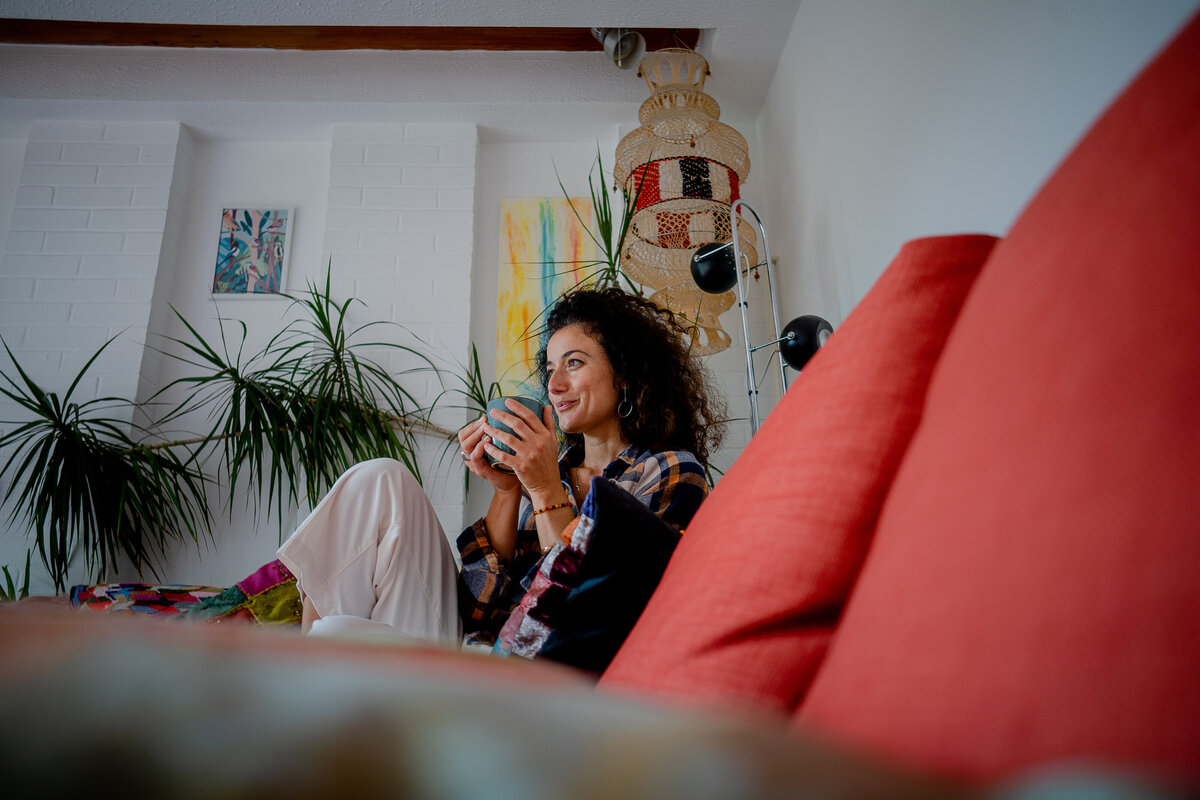 a person branding photograph of a woman with curly hair holding a cup of tea surrounded by plants