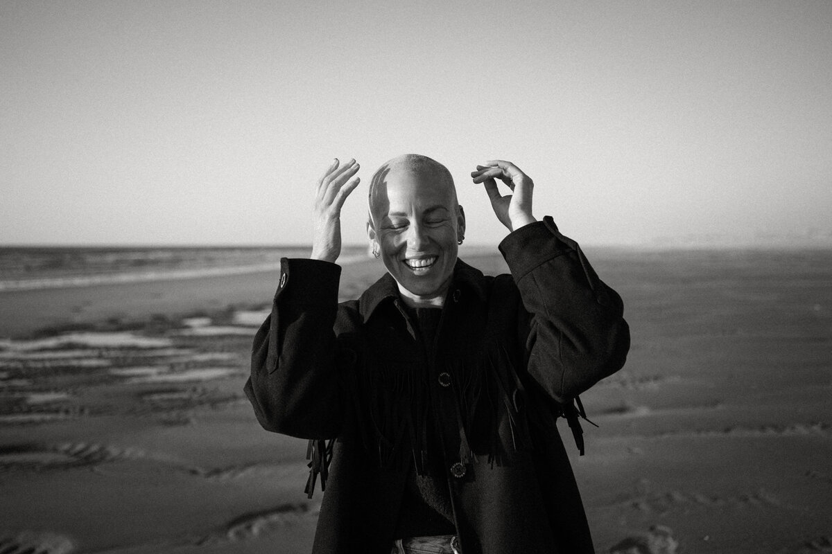 Vrouw met alopecia op het strand lacht