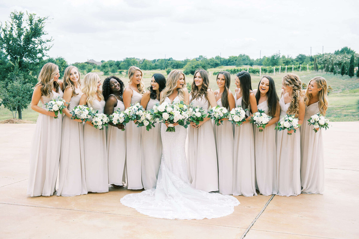 Bridal party smiles and poses outside of D'Vine Grace Vineyard wedding venue in Texas
