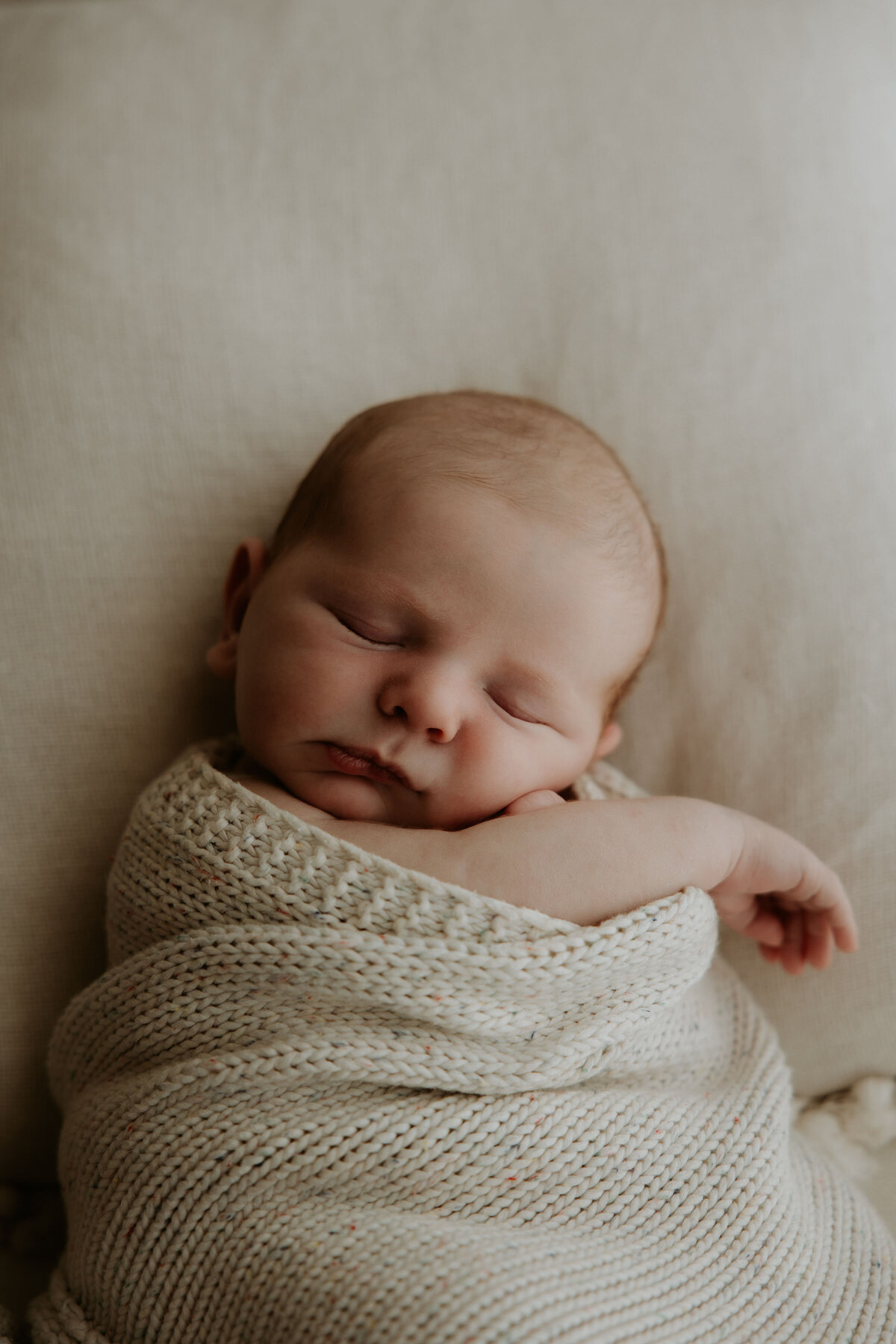 Sleeping newbron wrapped in blanket sleeps during studio newborn photoshoot