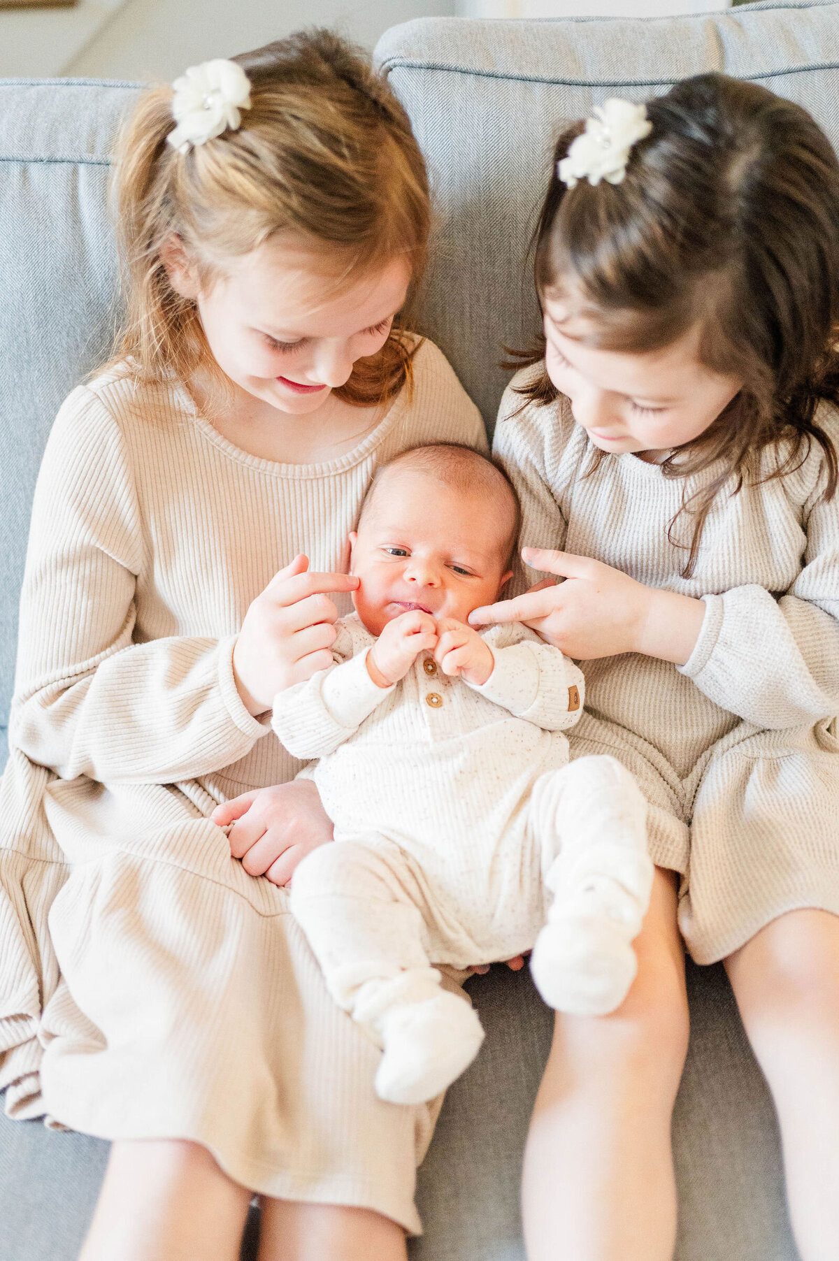 Newborn in Sutton, MA sitting in his sisters' arms