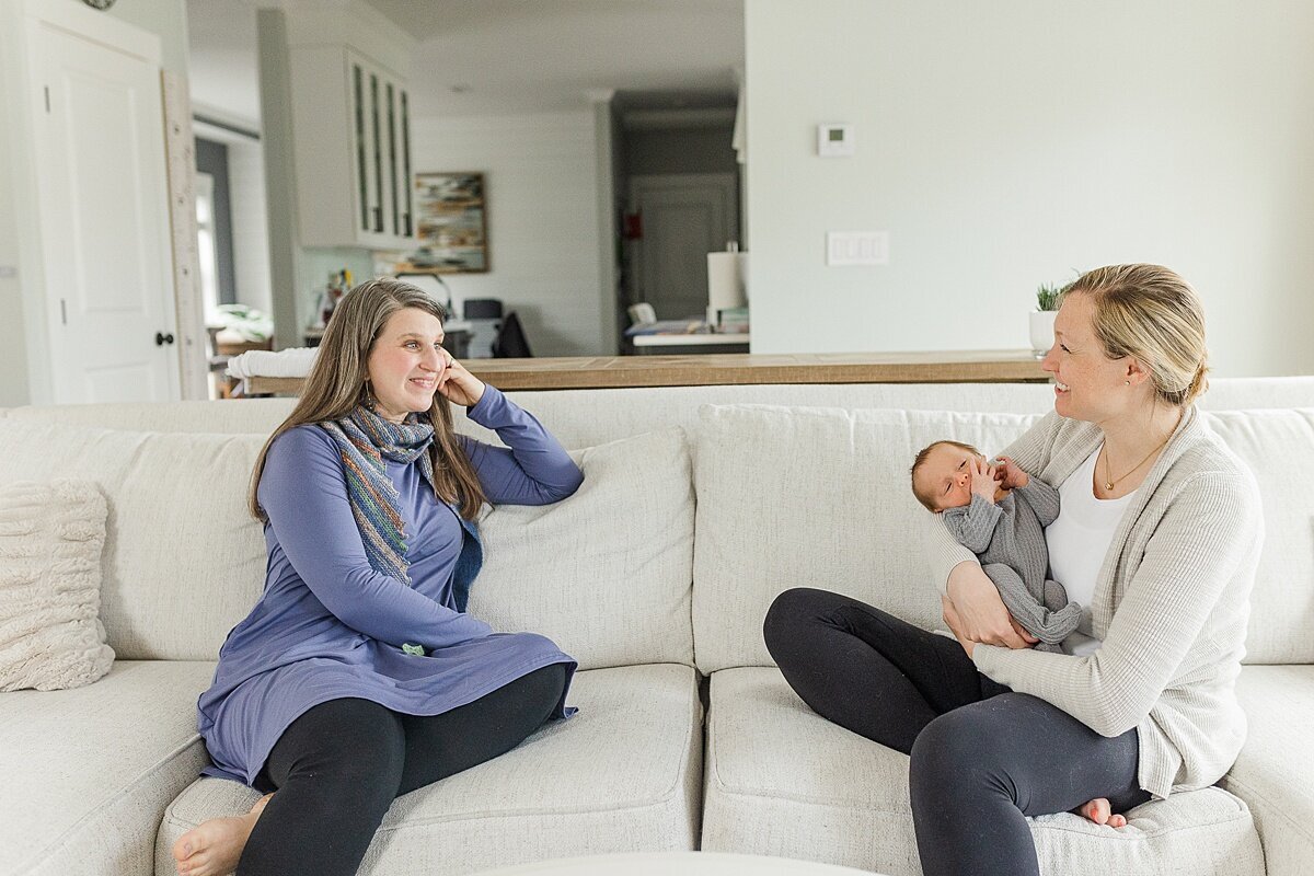 doula sits with a mother and baby during BURGEONING BUD POST PARTUM DOULA Branding photo session with Sara Sniderman Photography in Natick Massachusetts