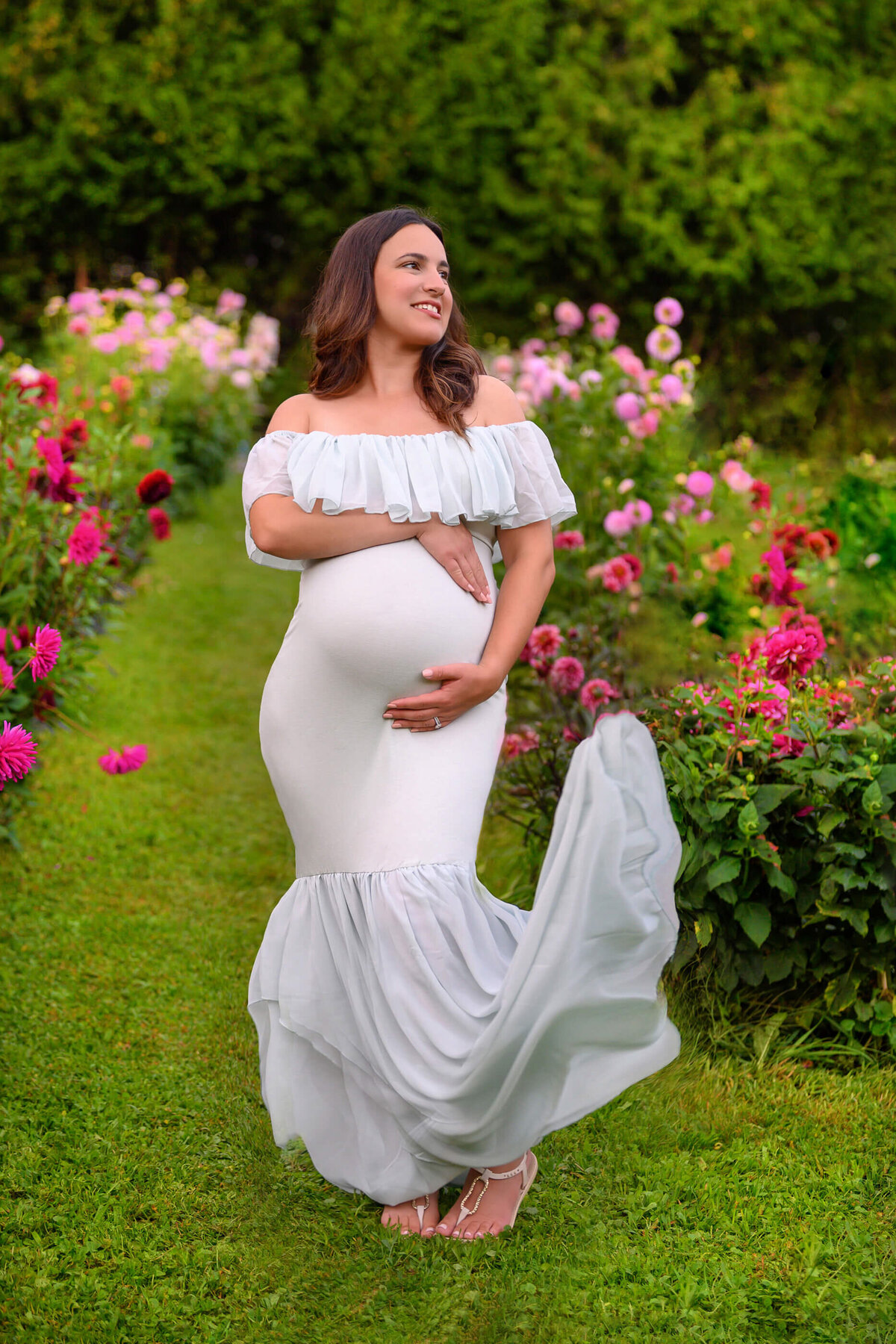 woman wearing a mint green maternity dress flowing in the wind for her outdoor maternity photography session in Burlington, On