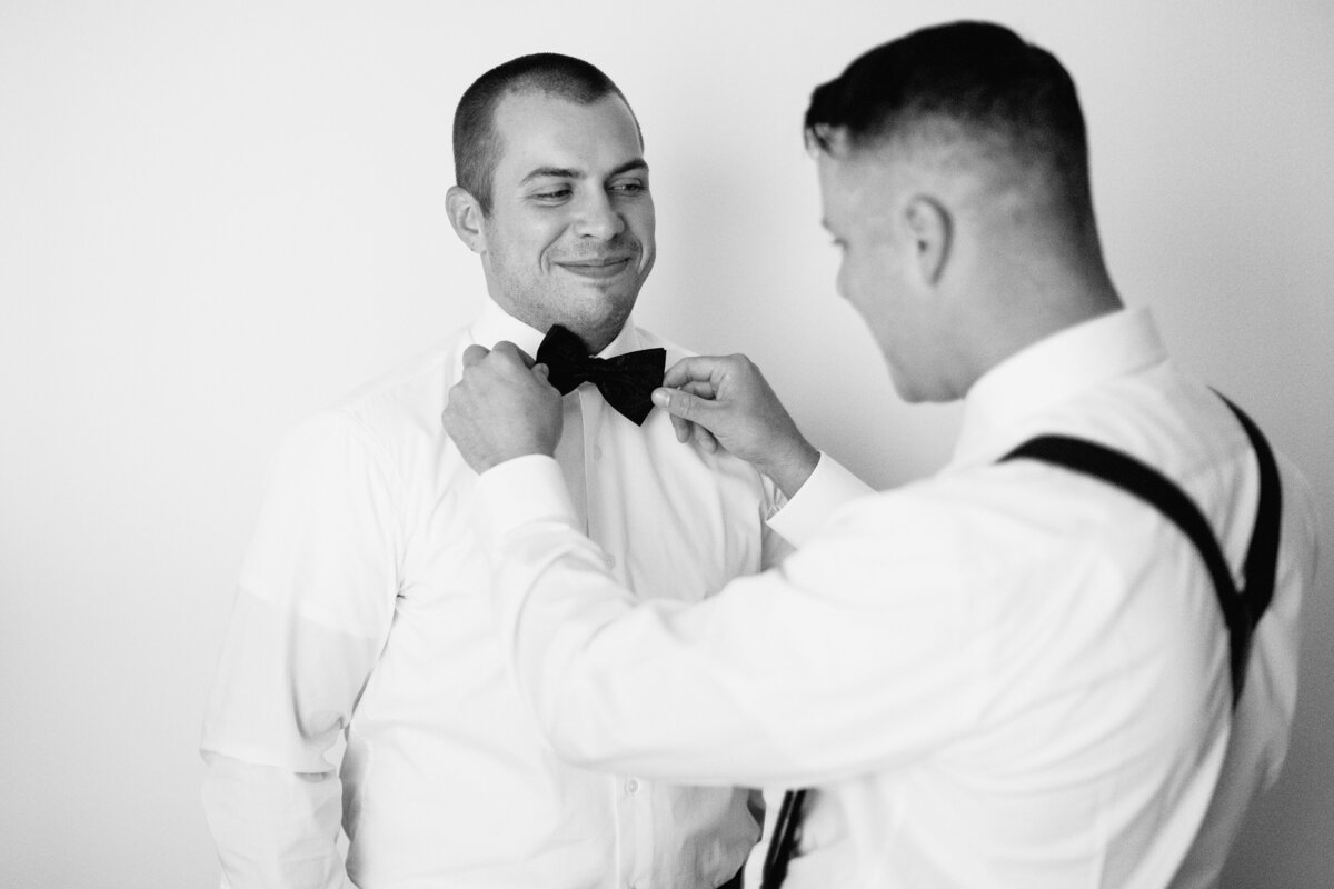 bestman helping groom with the bow tie