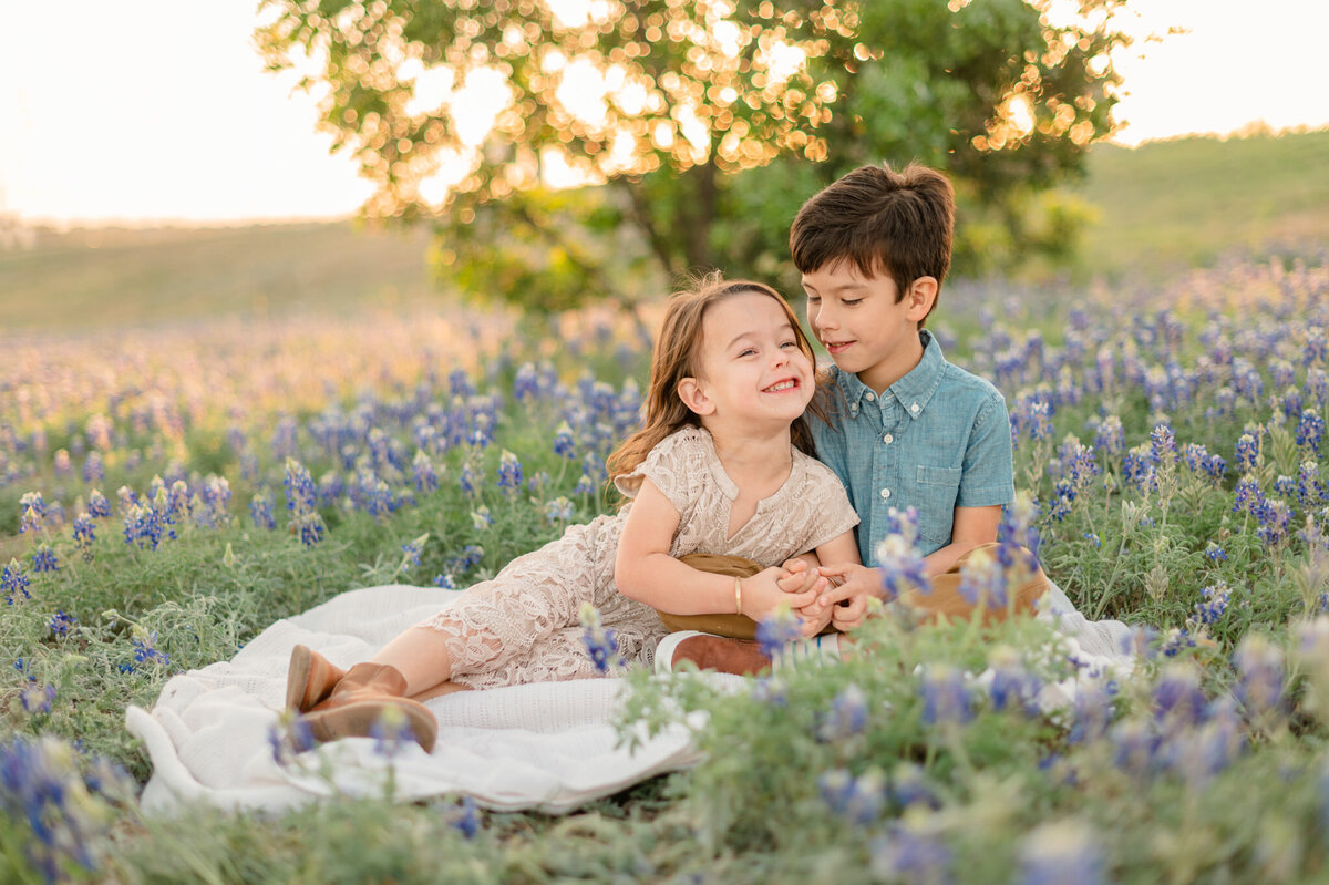Brother and sister smile together in San Antonio bluebonnets. Family photography by Cassey Golden.