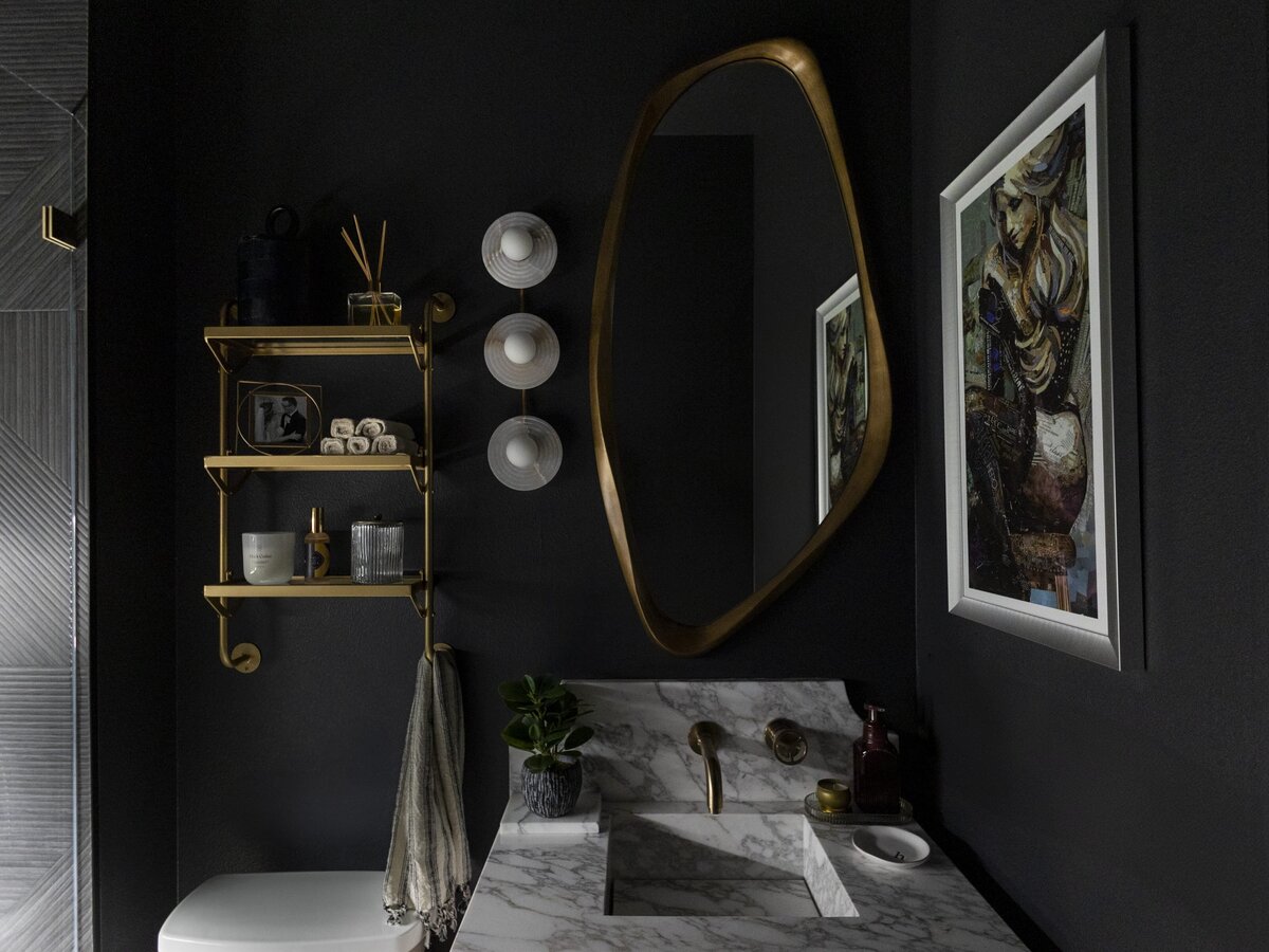 dewine design interiors moody guest bathroom with dark wall and gold organic shape mirror