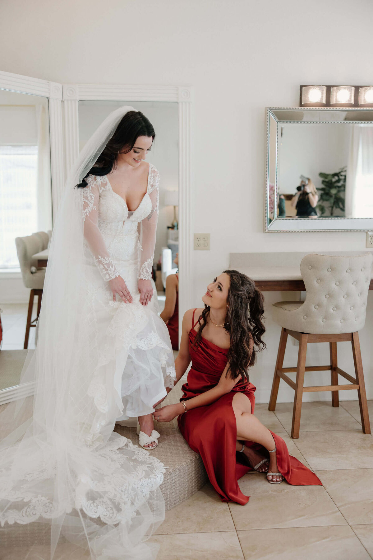 maid of honor helping bride to put on heels on wedding day