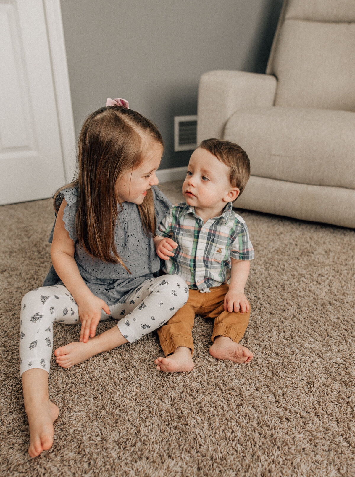 Milestone photo of two young children sitting next to each other smiling.