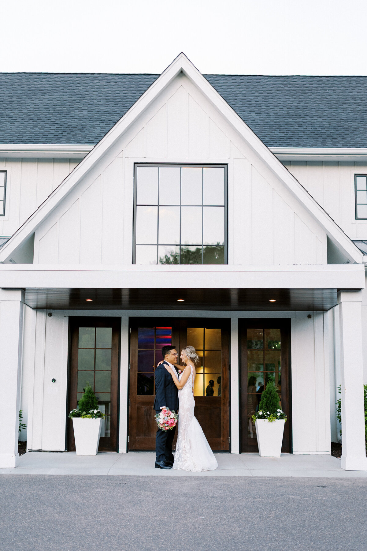 Bride and groom standing togather and looking at each other with smiles at The Hutton House