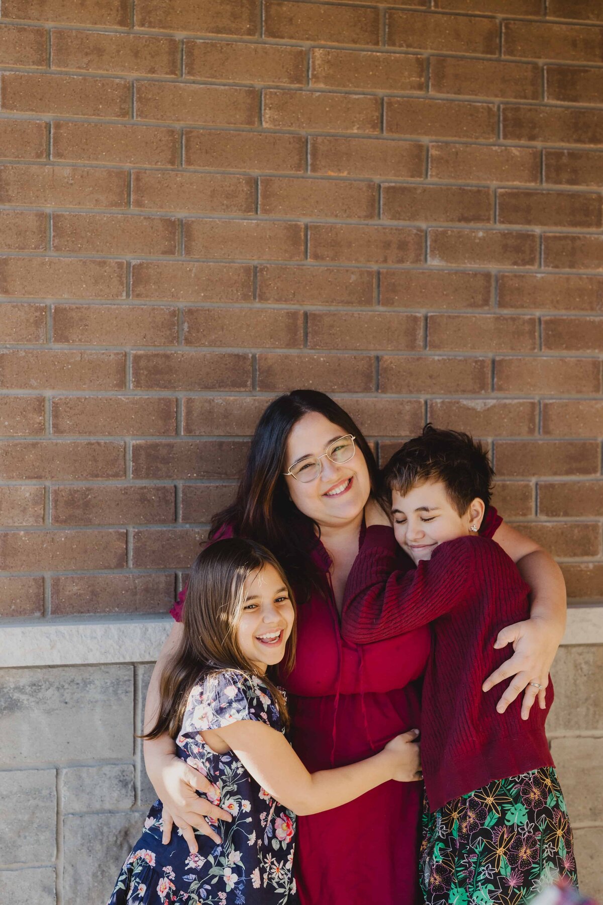 Valerie Doucette, a wedding, engagement, elopement, couples photographer, and her two daughters in a group hug as they smile for the camera