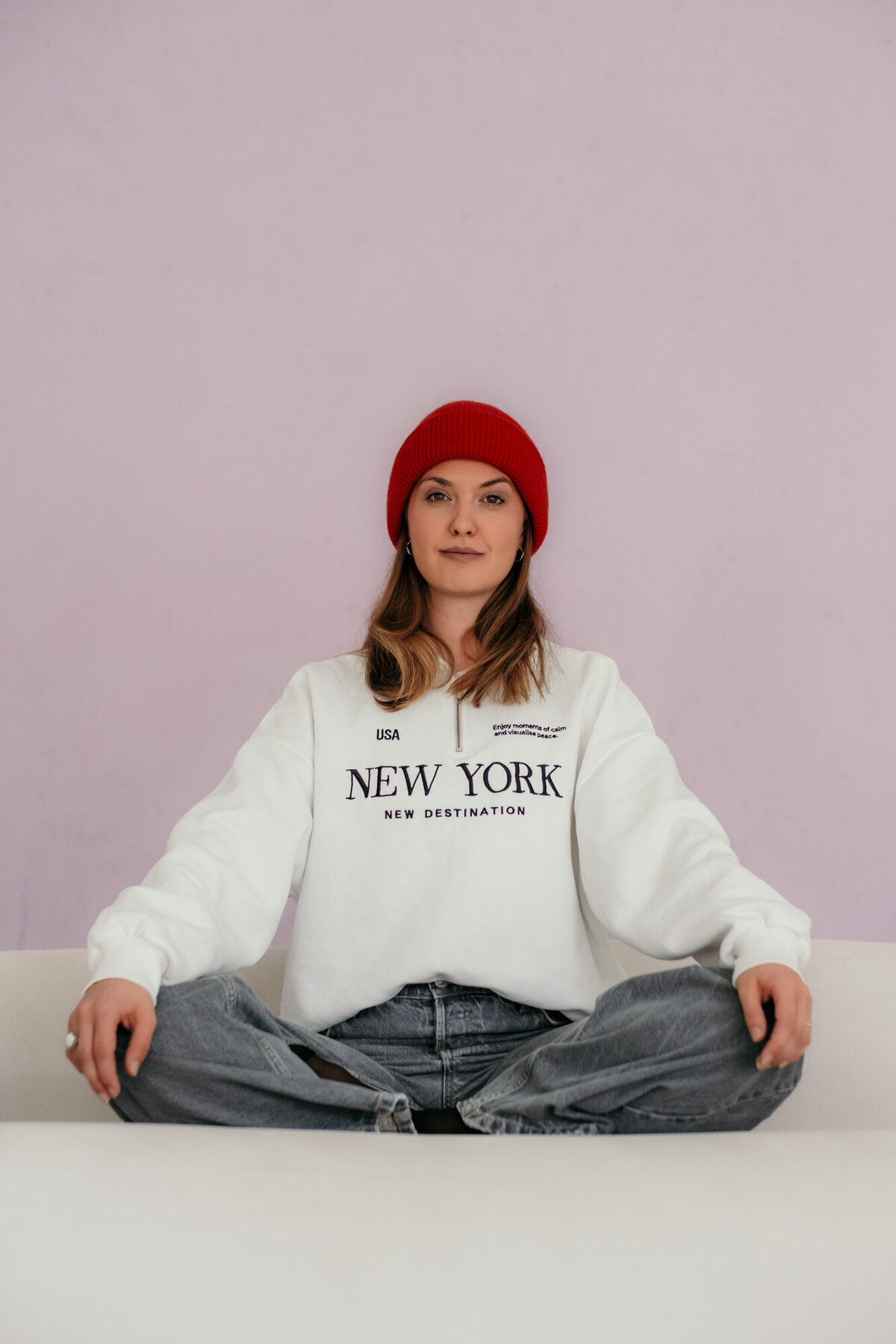 Woman sits with legs crossed on a sofa.