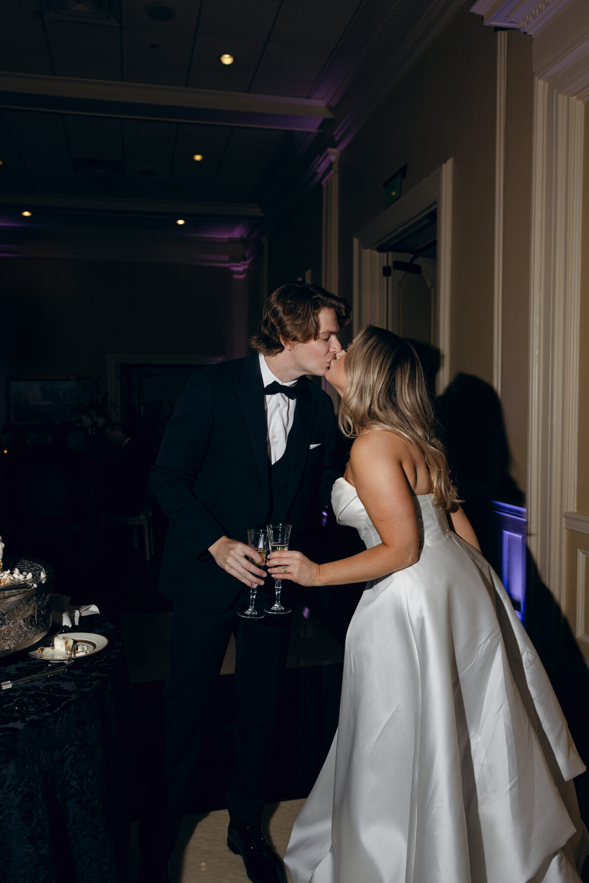A wedding photo of the bride and groom kissing after cutting their wedding cake