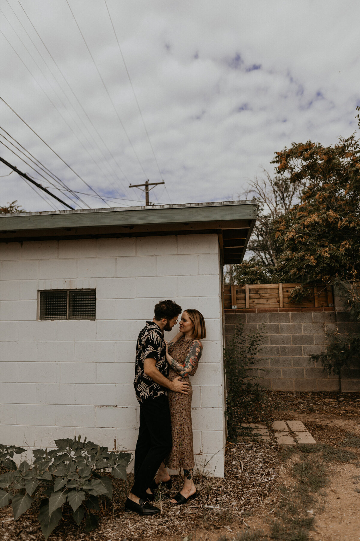 tattooed couple holding each other in southwestern backyard