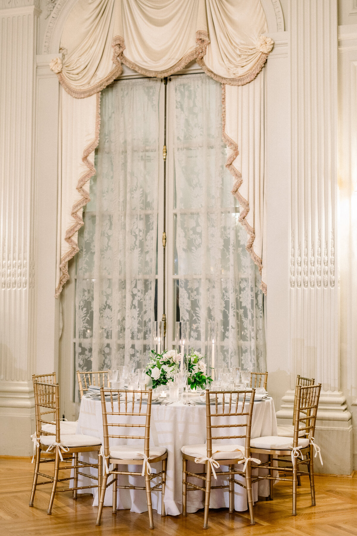 candle lit round tablescape  in ballroom of rosecliff mansion in newport rhode island
