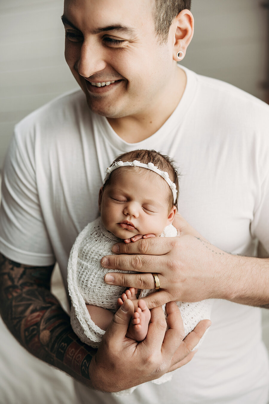 Baby girl in dad's hands while he smiles at mom