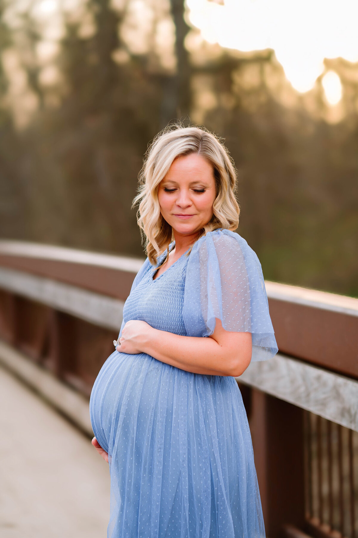 Expecting mother in a soft blue dress during sunset maternity portraits in Allen, Texas, captured by Jennifer L. Kirk Photography.