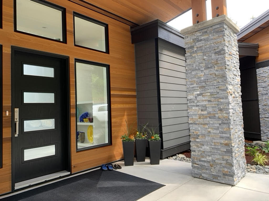Modern home entrance design with wrapped pillars, steel entry door and cedar surround by K2 Developments.