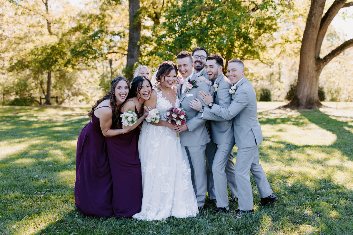 wedding party surrounding and hugging the bride and groom