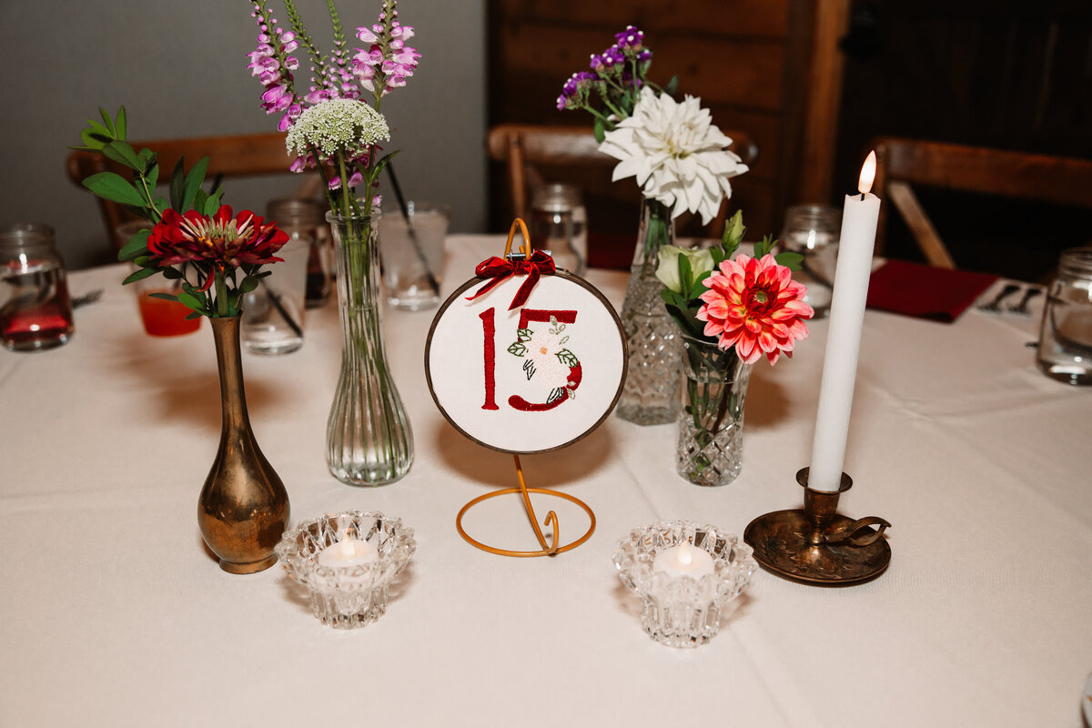 Details of a wedding reception table setting with flowers and tall candle