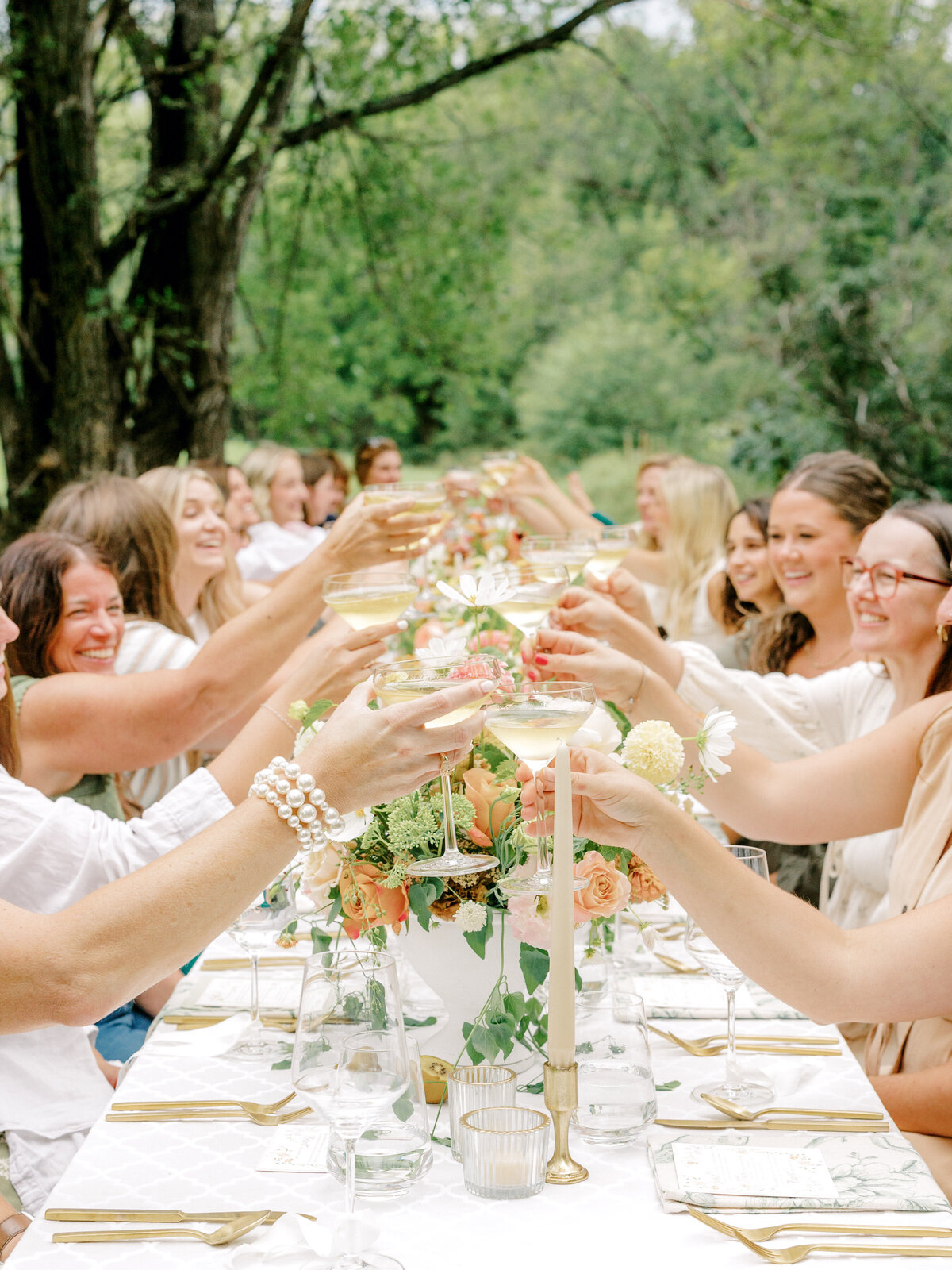 Wedding guests toasting and clinking glasses during dinner seated at a reception table