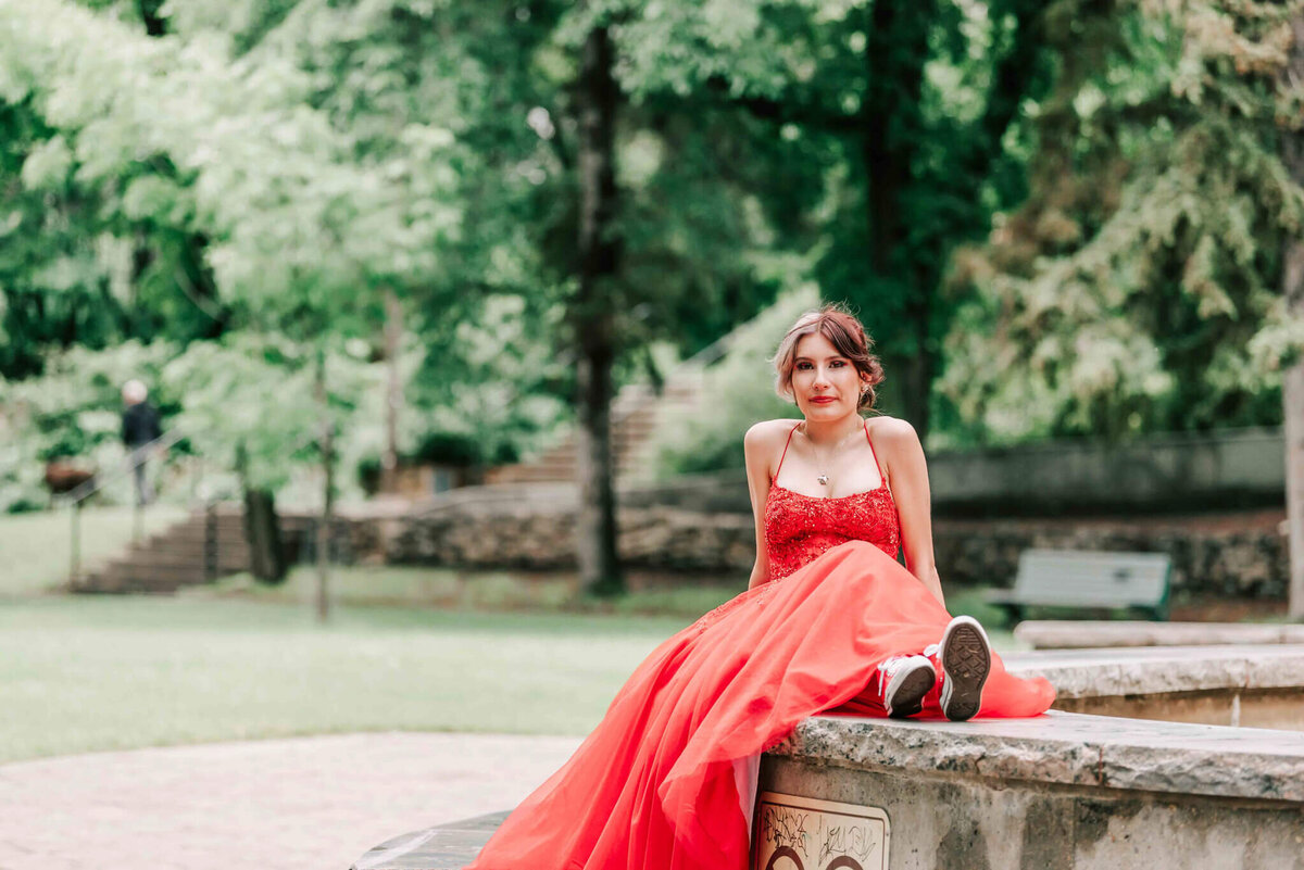 A pretty short haired girl sitting on the side of a fountain.