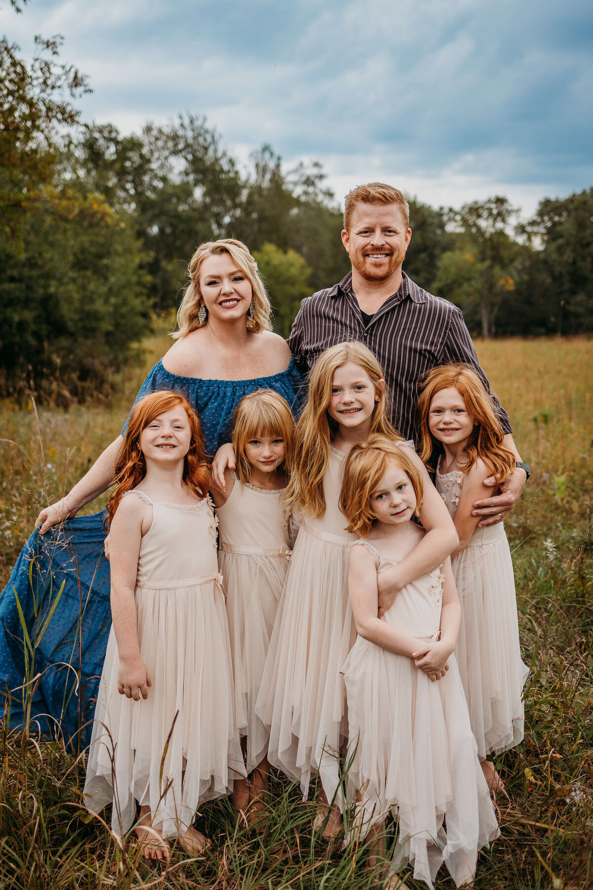 A beautiful family photo in field outdoors mom blue dress near eau claire wi with luci levon  photography, a family photography session