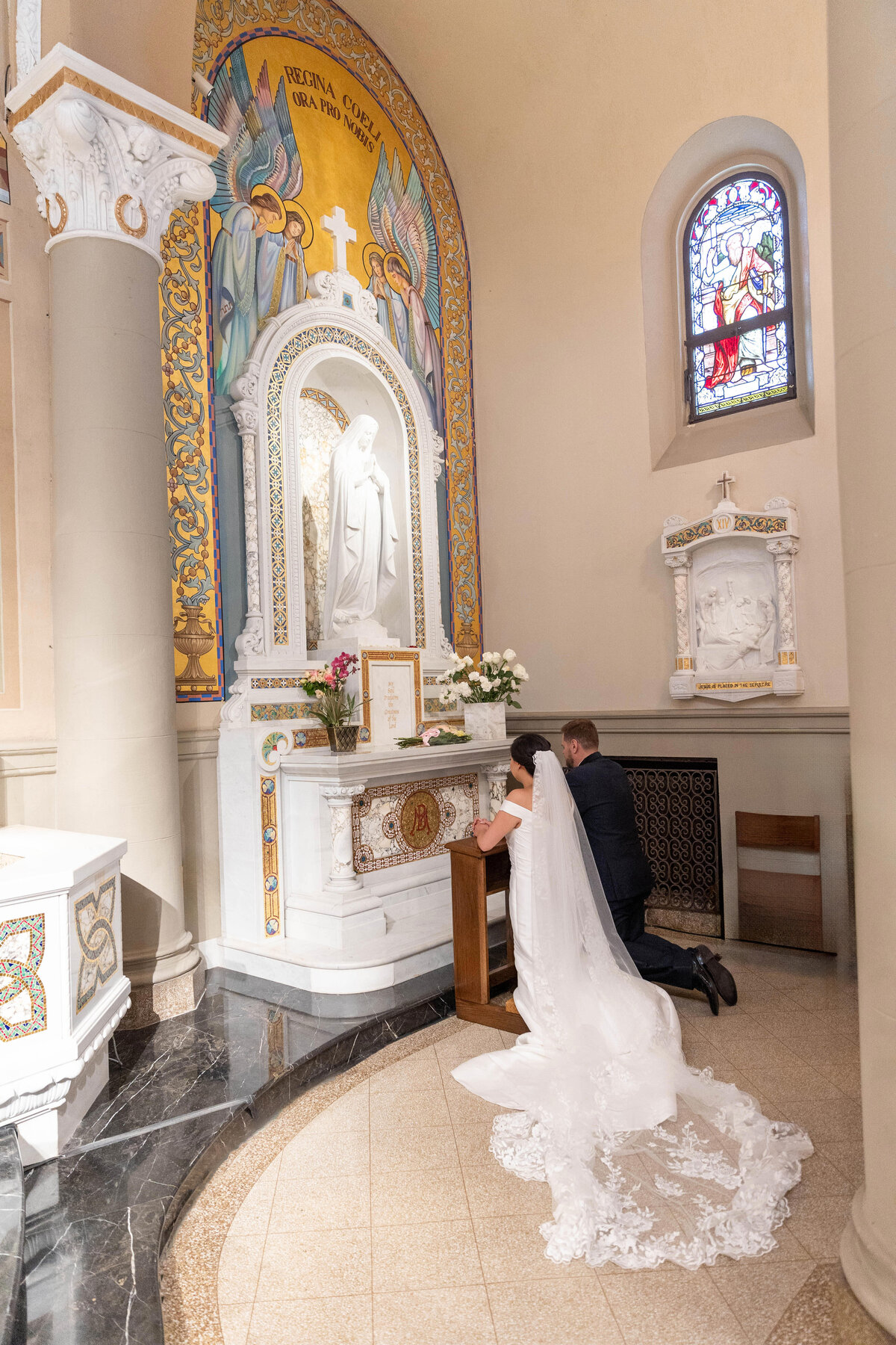 Bride and groom giving flowers to Virgen  Mary