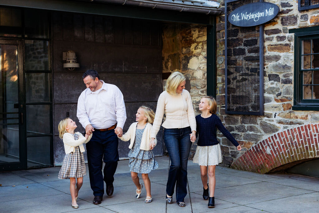 A family holds hands and walks outdoors.