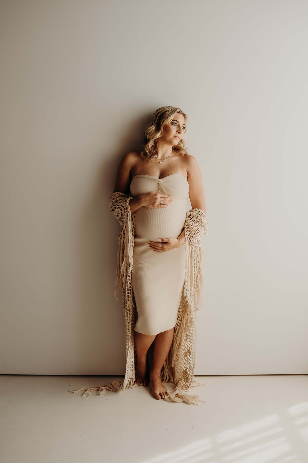 full length glamour portrait of pregnant woman looking towards the light