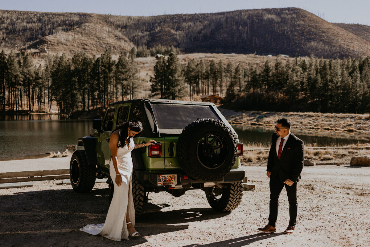 bride adn groom having a first look around the sides of their jeep wrangler