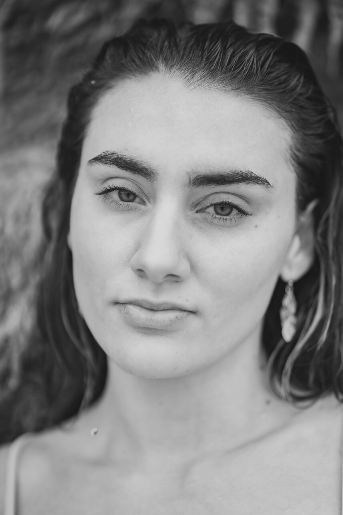 Close up headshot portrait in black and white of a young woman with her hair wet and slicked back