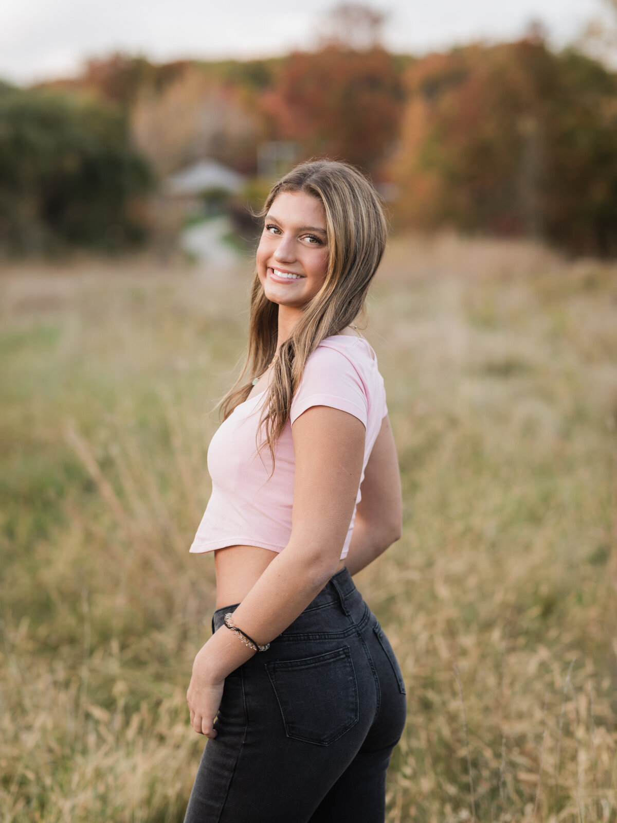 senior girl in pink top posing for senior photos in field at Westcreek Reservation in Parma, Ohio 