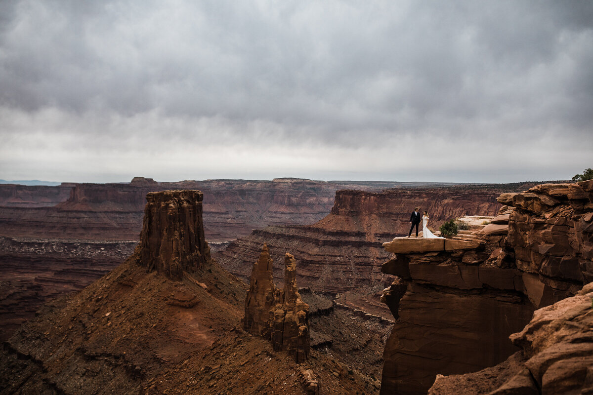 Holding his bride's hand, the groom leads the bride down a red rock during their arizona elopement