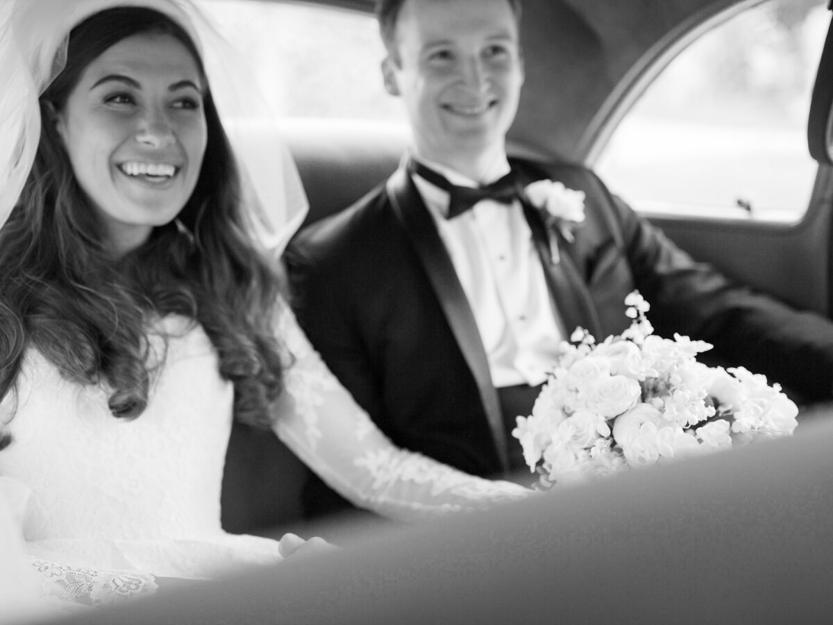 Bride and groom happily holding hands in back of car photographed by Chicago editorial wedding photographer Arielle Peters