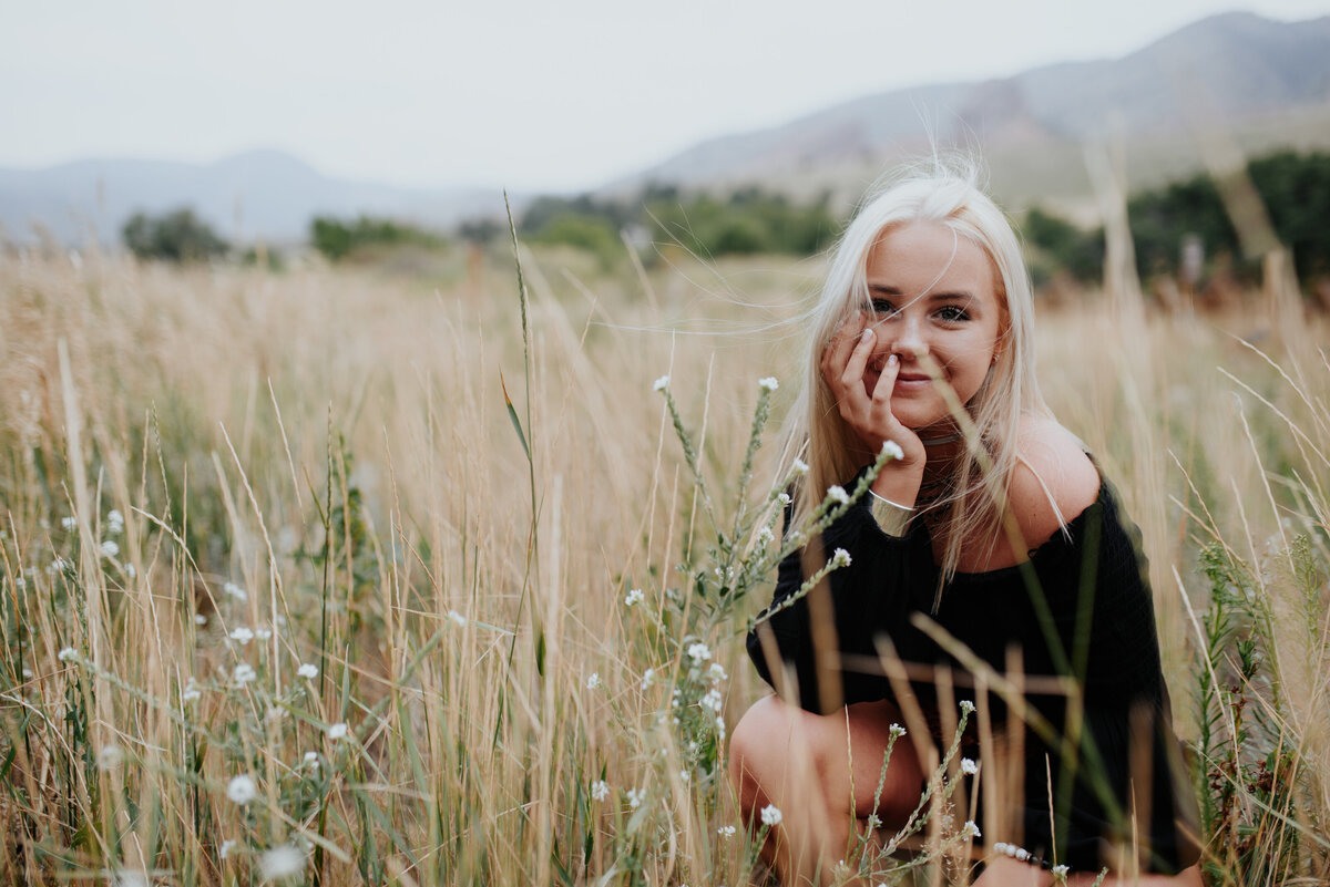 Natural photo of blonde smiling in a field among tall grass for high school graduation