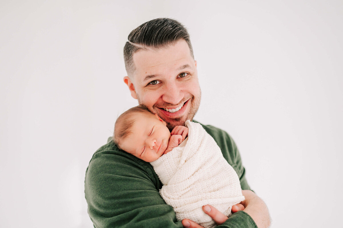 Branson Missouri newborn photographer Jessica Kennedy of The Xo Photography captures dad smiling holding newborn