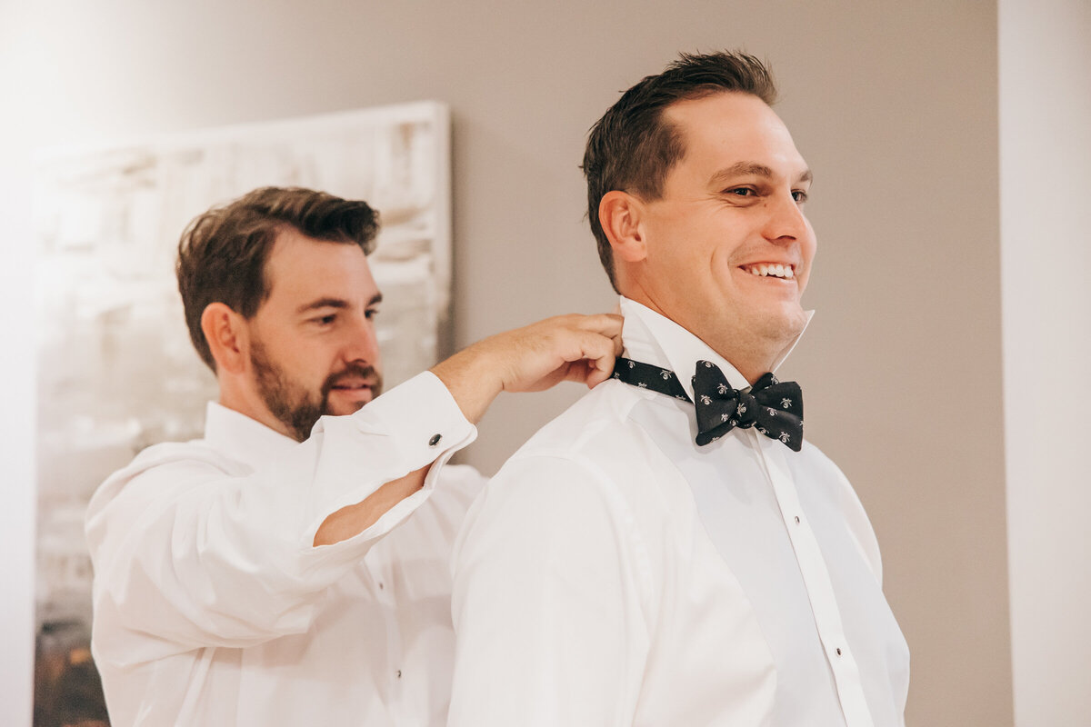 Best man putting on the groom's bow tie
