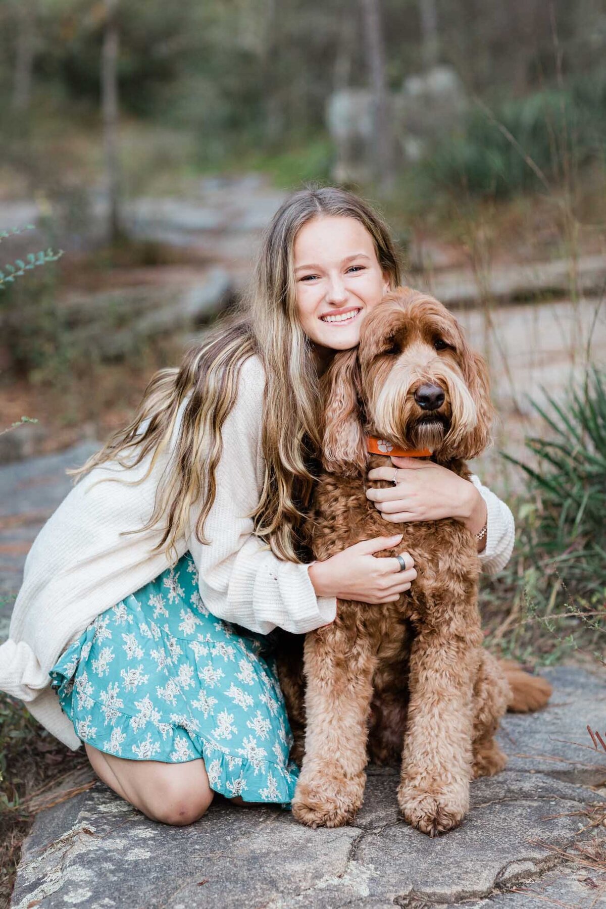 A girl hugging her labradoodle dog during her senior portrait.