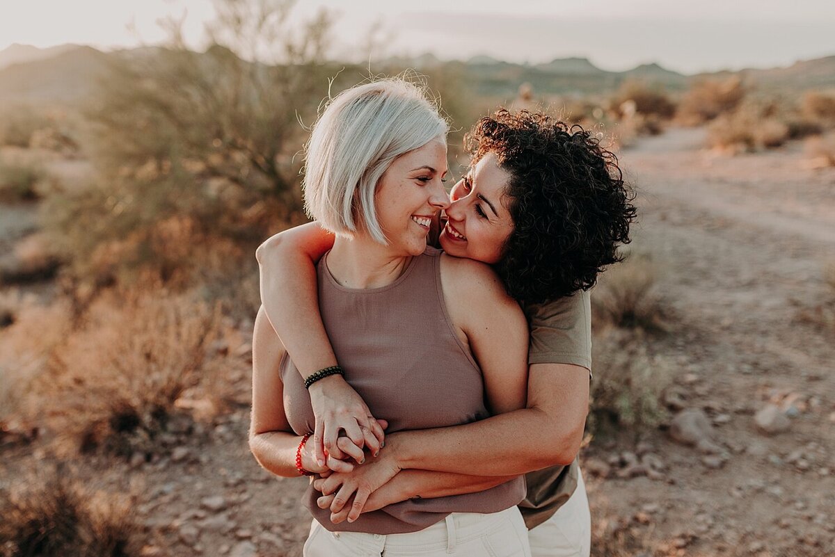 two women cuddle in the desert for their engagement session