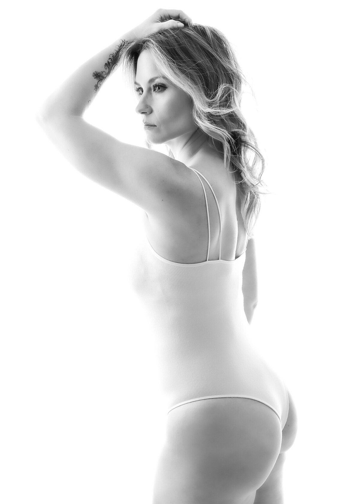 woman in white bodysuit with soft dreamy lighting with her hand in her hair