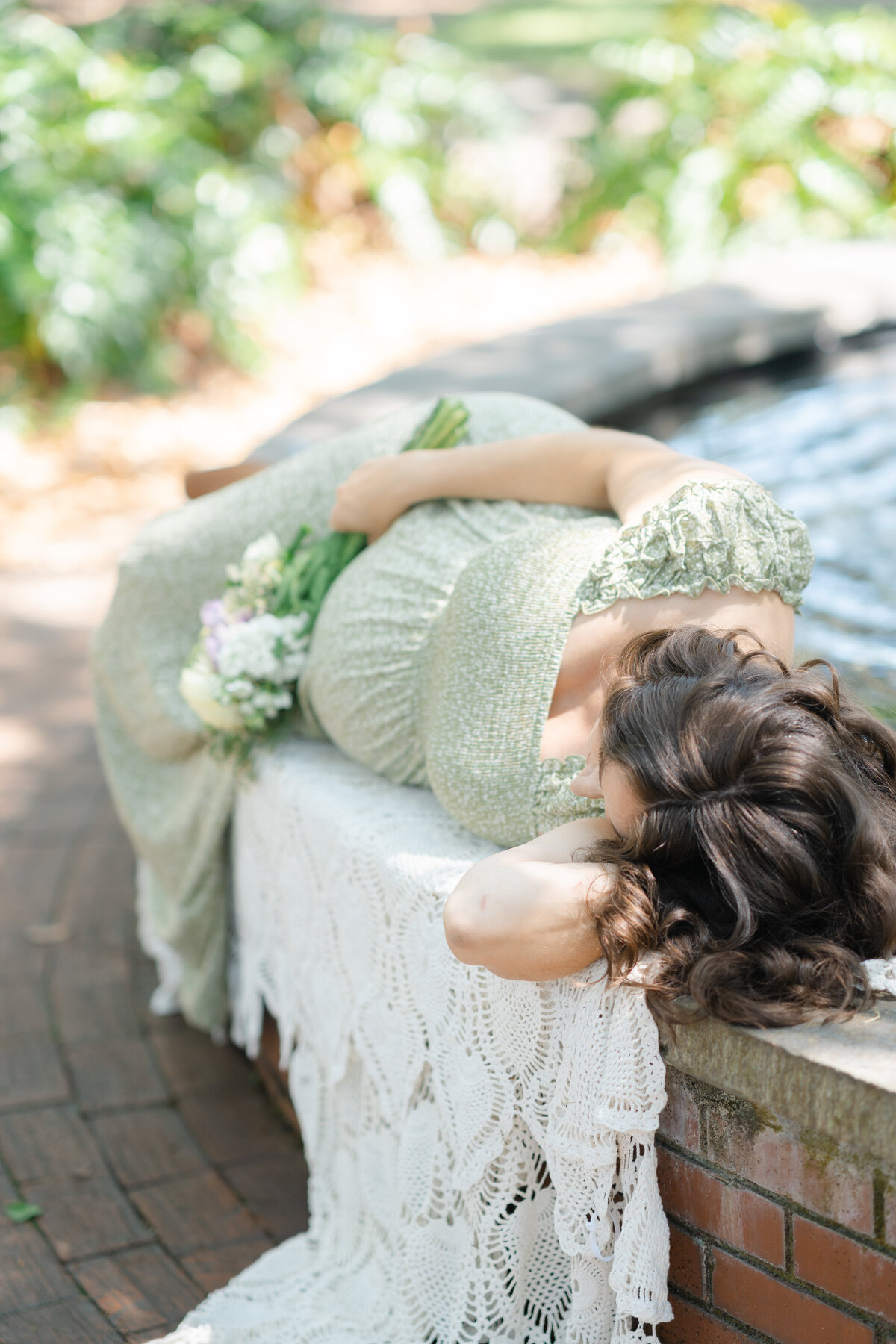 pregnant mother laying next to fountain in Lafayette square by Savannah family photographer Courtney Cronin